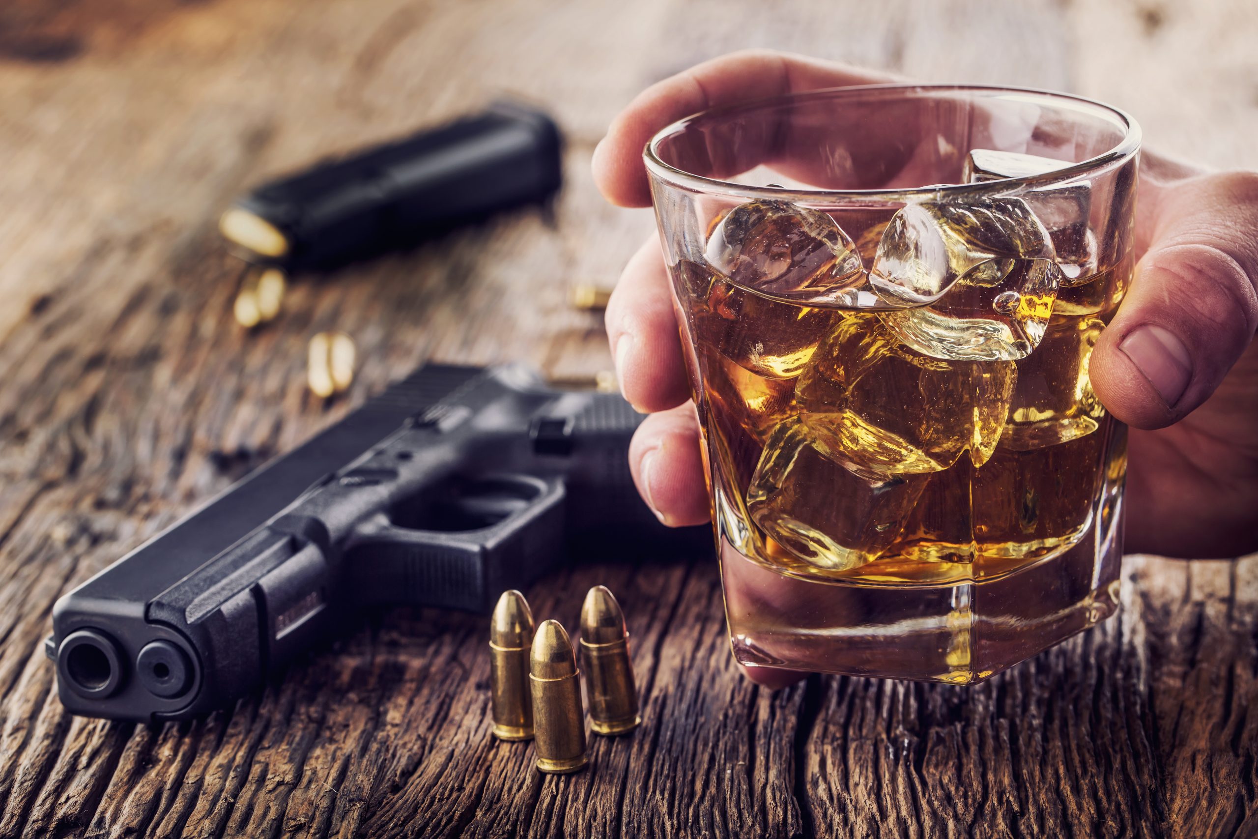 Gun and alcohol. 9mm pistol gun and cup whiskey cognac or brandy.